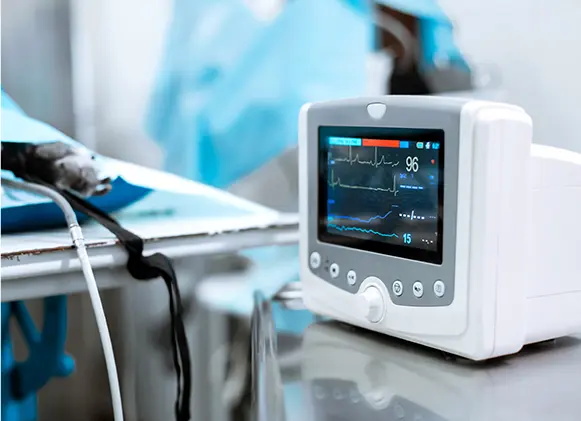 A medical monitor displaying ECG waveforms and vital signs like heart rate, with a draped patient’s limb in a sterile vete… A medical monitor displaying ECG waveforms and vital signs like heart rate, with a draped patient's limb in a sterile vete...